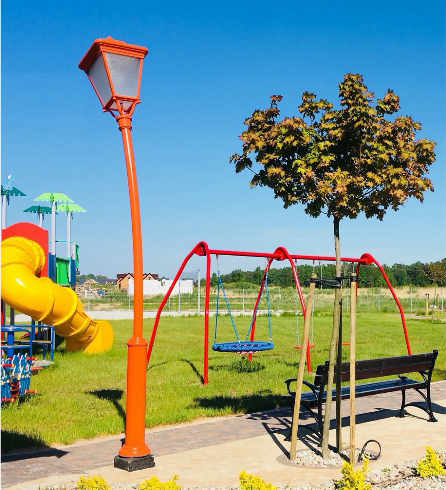 Stor orange lekfull armatur ståendes på en lekpark bredvid en gunga